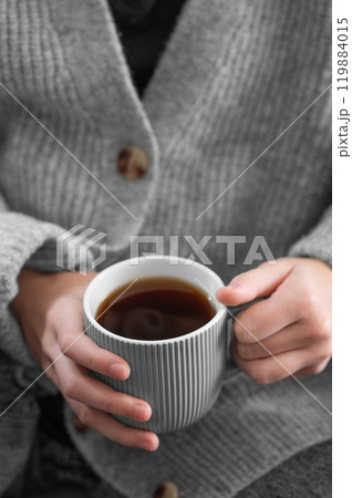 Woman in grey cozy sweater holding mug with espresso coffee close up. Woman in grey cozy sweater holding mug with espresso coffee close up. 119884015
