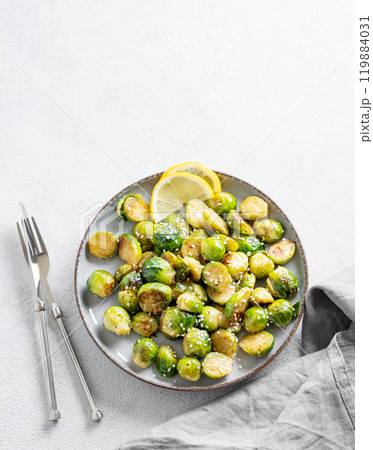 Fried brussels sprouts in a plate with soy or balsamic sauce, lemon and sesame on a light background Fried brussels sprouts in a plate with soy or balsamic sauce, lemon and sesame on a light background 119884031