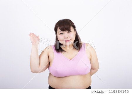 白い背景の前で右手を上げるスポーツブラの太った若い女性 白い背景の前で右手を上げるスポーツブラの太った若い女性 119884146