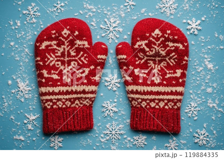 Cozy red mittens with snowflake pattern on a blue snowy background 119884335