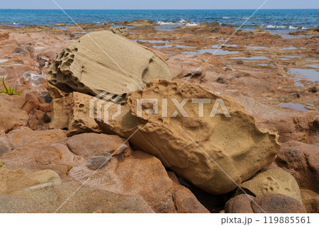 Weathered Rocks on Coastal Terrain with Sea in Background 119885561