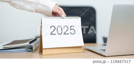 Business woman change 2025 Year Calendar on table with laptop computer during working and writing in office. countdown, Happy New Year, Resolution, Year End and New Start and Goals Plan Action Concept Business woman change 2025 Year Calendar on table with laptop computer during working and writing in office. countdown, Happy New Year, Resolution, Year End and New Start and Goals Plan Action Concept 119887317