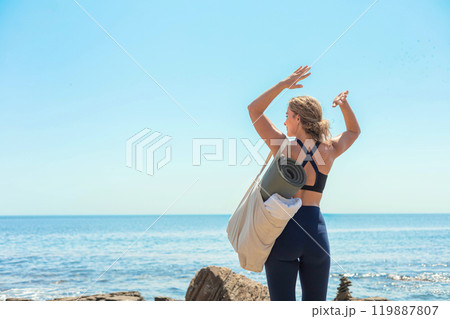 Active fitness yoga woman standing on cliff beach contemplate sea sky sunny landscape back view 119887807