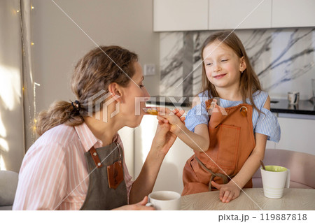 Little girl treats her mother with Christmas gingerbread that she made herself. Little girl treats her mother with Christmas gingerbread that she made herself. 119887818