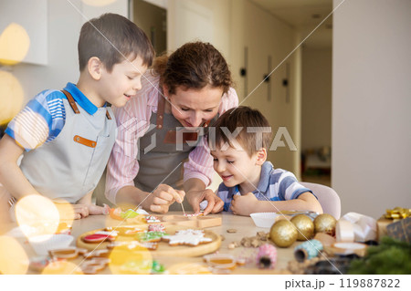Happy family mother and children in aprons making Christmas cookies together while cooking Happy family mother and children in aprons making Christmas cookies together while cooking 119887822