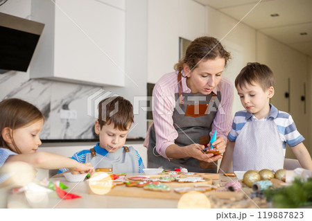 Happy family mother and children in aprons making Christmas cookies together while cooking Happy family mother and children in aprons making Christmas cookies together while cooking 119887823