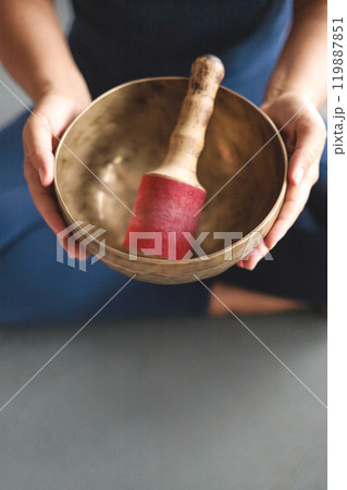 Yoga woman in lotus position hands holding singing meditation bowl top view closeup Yoga woman in lotus position hands holding singing meditation bowl top view closeup 119887851