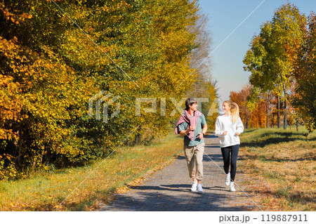 Sporty family couple morning jogging in city autumn beautiful park. Young active mans runners Sporty family couple morning jogging in city autumn beautiful park. Young active mans runners 119887911
