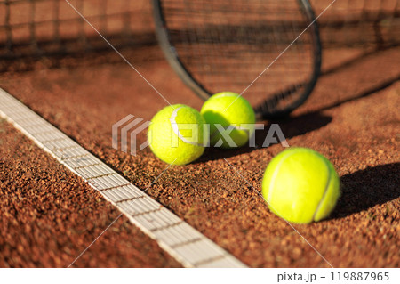 Tennis ball with rocket near grid at outdoor summer sunny court closeup 119887965