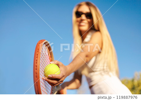 Woman tennis player tossing ball hitting racket at summer sunny outdoor court closeup Woman tennis player tossing ball hitting racket at summer sunny outdoor court closeup 119887976