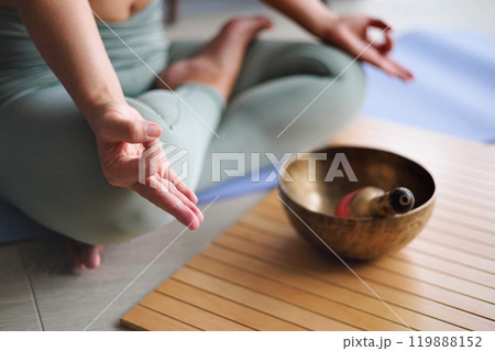 Woman in lotus position practicing yoga singing meditation bowl on wooden board top view closeup Woman in lotus position practicing yoga singing meditation bowl on wooden board top view closeup 119888152
