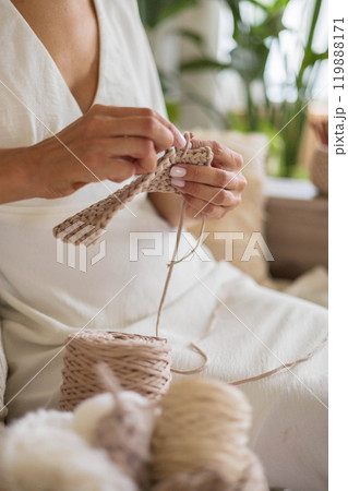 Close-up of young woman's hands. Girl crocheting from beige cotton yarn. Close-up of young woman's hands. Girl crocheting from beige cotton yarn. 119888171