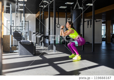 Fitness woman making squat with rubber band training butts at sportive gym Fitness woman making squat with rubber band training butts at sportive gym 119888187