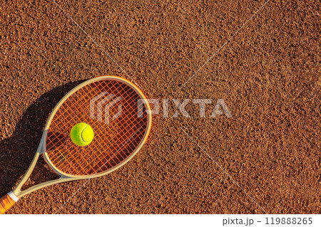 Yellow tennis ball lying on rocket at outdoor summer sunny court ground closeup 119888265