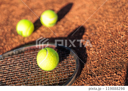 Tennis ball with rocket near grid at outdoor summer sunny court closeup Tennis ball with rocket near grid at outdoor summer sunny court closeup 119888298