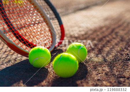 Tennis ball with rocket near grid at outdoor summer sunny court closeup 119888332