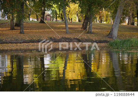 Serene autumn park with vibrant foliage reflecting in calm river water creating a peaceful landscape Serene autumn park with vibrant foliage reflecting in calm river water creating a peaceful landscape 119888644