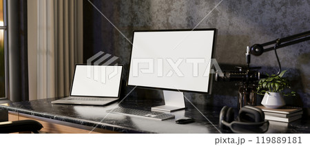 A modern loft podcaster office workspace featuring multiple screens from a laptop and a computer. A modern loft podcaster office workspace featuring multiple screens from a laptop and a computer. 119889181