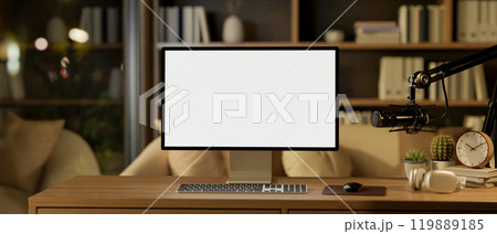 A contemporary home podcast office at night features a computer with a white screen mockup. 119889185