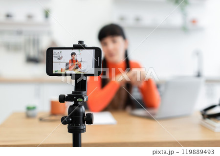 Young woman recording video blog at home using smartphone 119889493