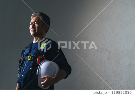 ニッカポッカを着てヘルメットを持ったシニア男性職人 ニッカポッカを着てヘルメットを持ったシニア男性職人 119891050