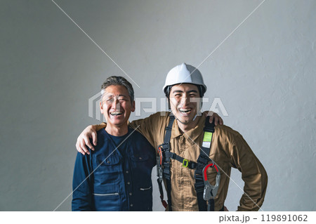 笑顔で肩を組む職人と作業員 笑顔で肩を組む職人と作業員 119891062