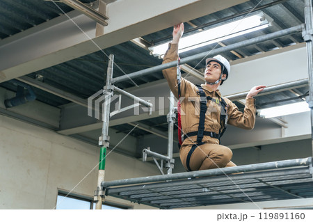 建設現場の足場に登って高所作業する作業員 119891160