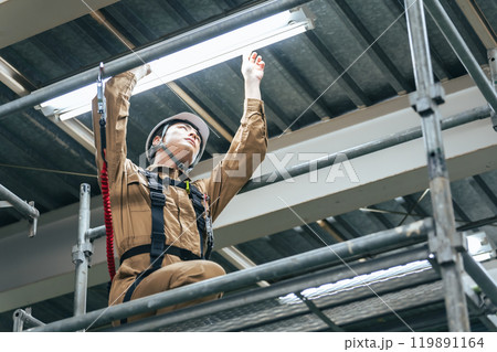 建設現場の足場に登って高所作業する作業員 119891164