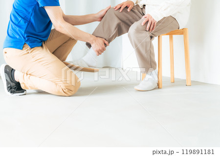 シニア男性のひざの痛みを診察するケアスタッフ 119891181
