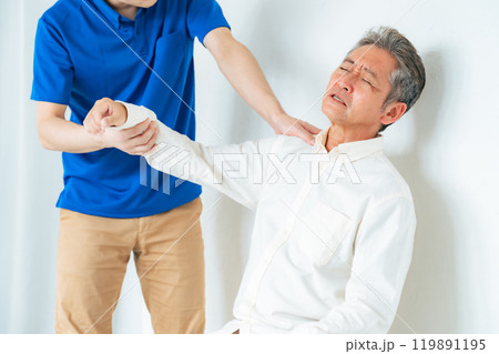 シニア男性の肩の痛みを診察するケアスタッフ 119891195