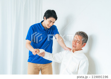シニア男性の肩の痛みを診察するケアスタッフ 119891196
