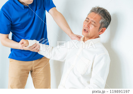 シニア男性の肩の痛みを診察するケアスタッフ 119891197