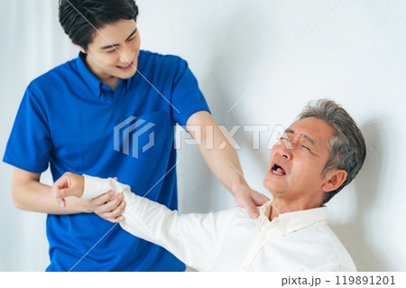 シニア男性の肩の痛みを診察するケアスタッフ 119891201