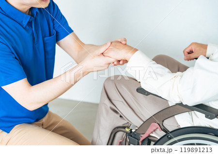 車椅子に乗ったシニア男性をサポートするケアスタッフ 車椅子に乗ったシニア男性をサポートするケアスタッフ 119891213