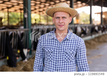 Confident man cow breeder standing in outdoor cowshed 119891549