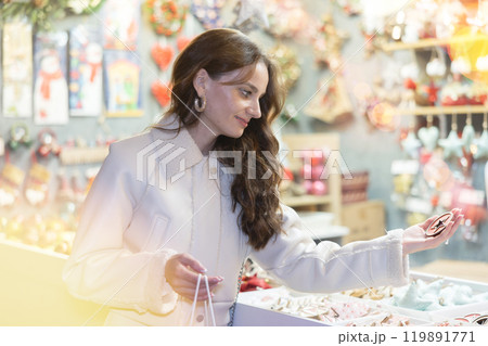 Smiling woman choosing festive home decorations on street Christmas fair 119891771