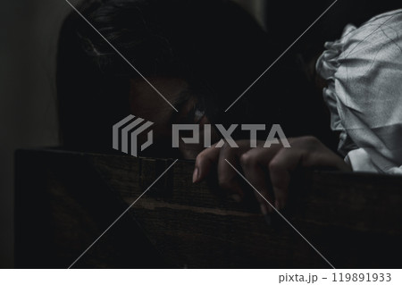 Horror ghost woman. Asian ghost horror creepy scary hair covering face and eye lying in the old treasure chest she look at camera, female makeup terror zombie face, murder, Happy Halloween day concept 119891933