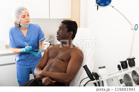 Woman cosmetician consulting man before cosmetological body treatment Woman cosmetician consulting man before cosmetological body treatment 119891991