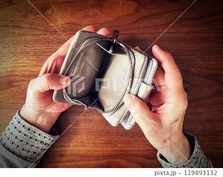 机の上で空っぽの財布を開ける高齢女性の手 119893132