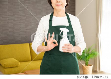 家のリビングで丸サインをする緑のエプロンをしたシニア女性の主婦・家政婦 家のリビングで丸サインをする緑のエプロンをしたシニア女性の主婦・家政婦 119894255