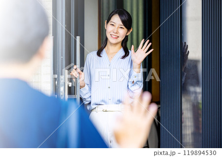玄関で手を振る夫婦 119894530
