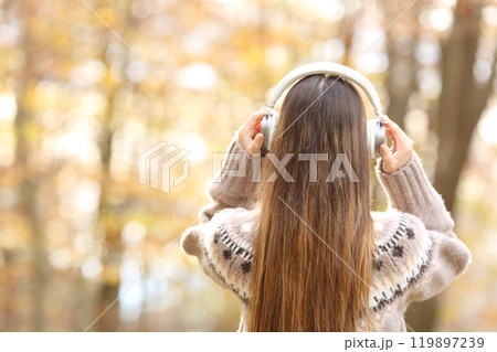 Back view of woman putting headphones in autumn 119897239
