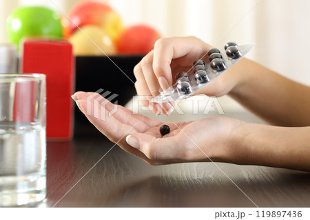 Woman hand getting a vitamin complex pill Woman hand getting a vitamin complex pill 119897436
