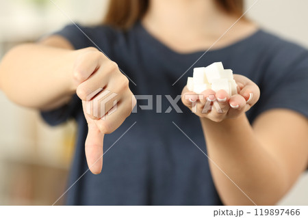 Woman hand holding sugar cubes with thumbs down Woman hand holding sugar cubes with thumbs down 119897466
