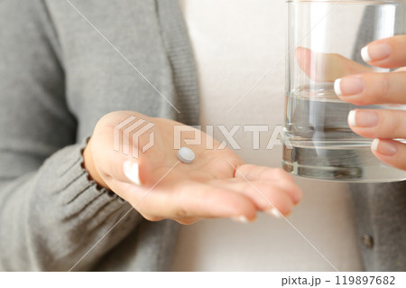 Woman hands holding a pill and a water glass 119897682