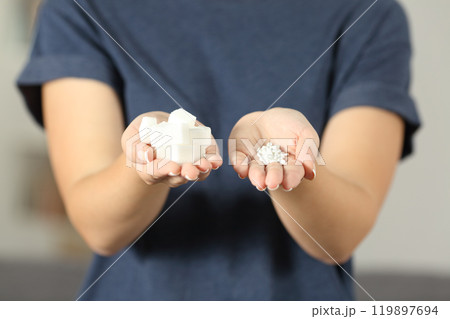 Woman hands holding sugar cubes and saccharin pills 119897694