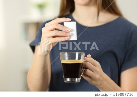 Woman hands throwing saccharin into a coffee cup 119897716