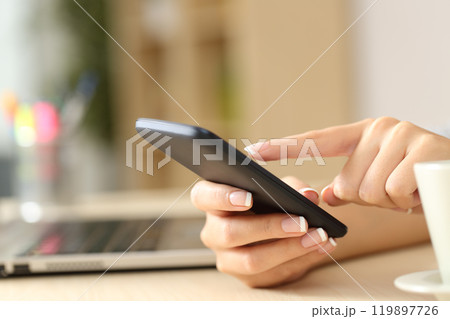 Woman hands using cell phone on a desk at home 119897726
