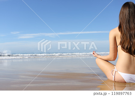 Woman practicing yoga exercises on the beach in summer 119897763