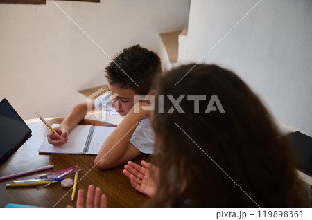Boy studying at home while woman helps with homework 119898361